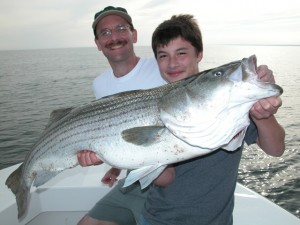 A father and son with a trophy striped bass caught on Captain Eric stapelfeld's hairball charters